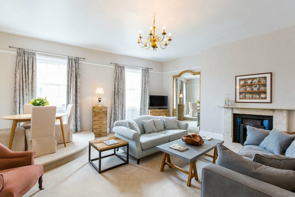 A spacious and airy living room with two sofas, a coffee table, and a dining table. It is nicely decorated with a muted colour palette.